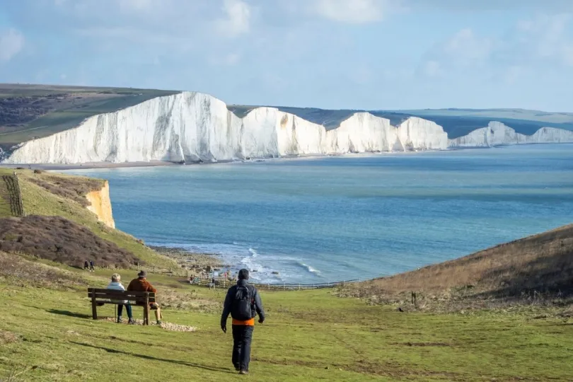 Een vrouw wandelt in Dover met op de achtergrond de witte kliffen.