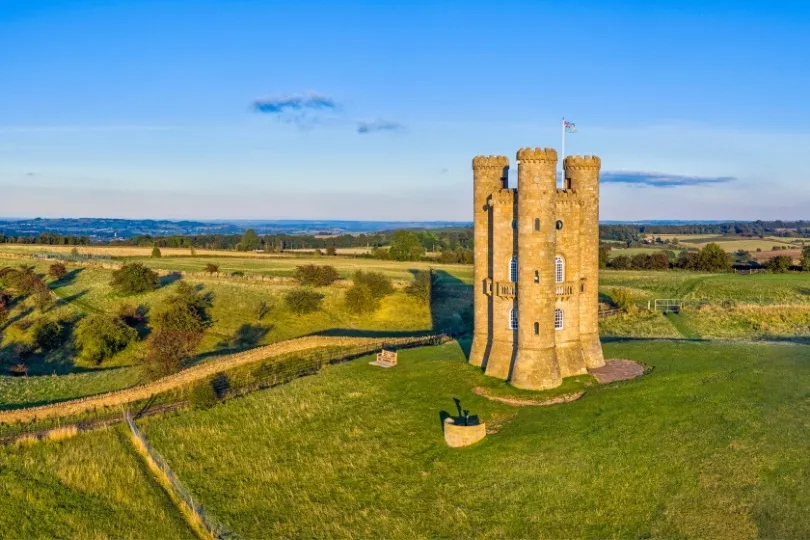 Een ronde stenen toren staat midden in een uitgestrekt groen landschap.