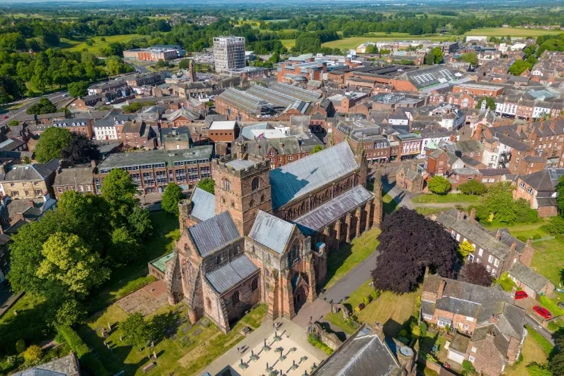Een grote kathedraal ligt midden in een historische stad, omringd door straten en gebouwen.