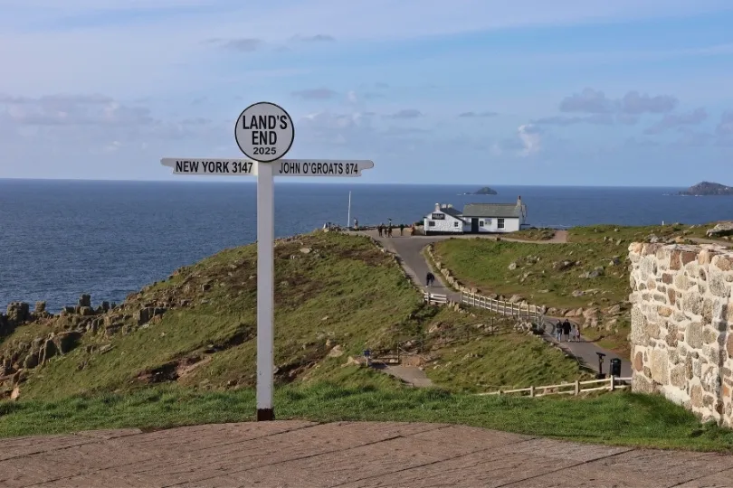 Een weg leidt naar de beroemde wegwijzer van Land's End met uitzicht over de zee.