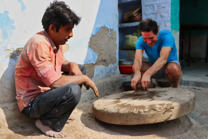 Een reiziger en een lokale man in India aan het pottenbakken - LIMITED RIGHTS DAISY.