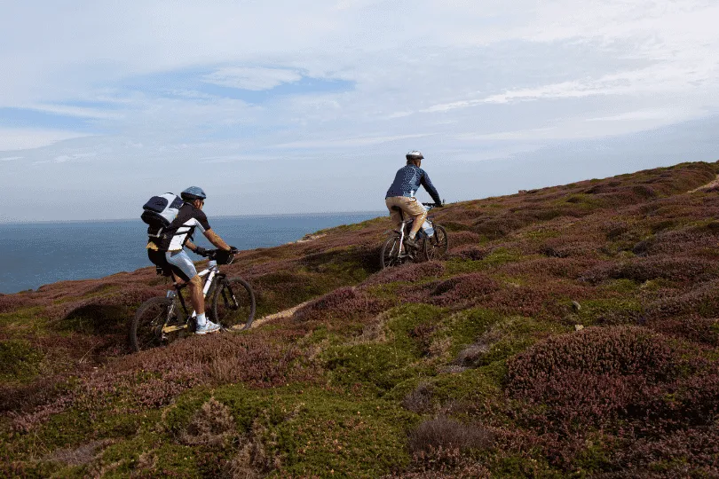 Twee fietsers die fietsen over een zandpad langs de kust van Jersey.