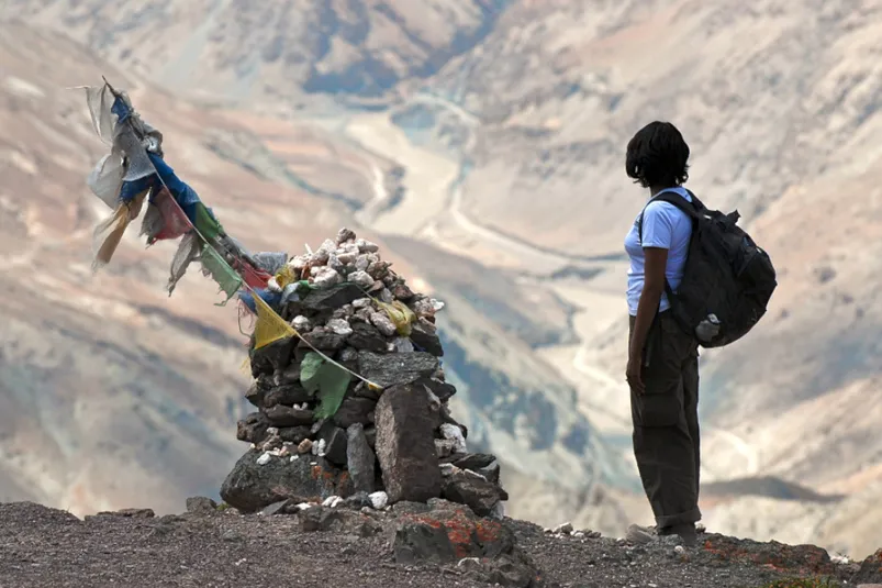 Ladakh trekking - reiziger tegenover stenen met vlaggetjes.