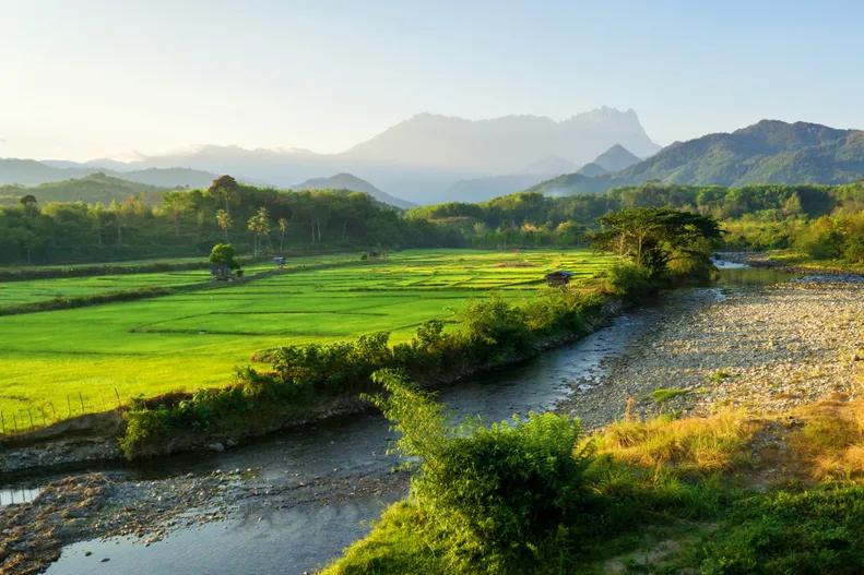 Maleisisch Borneo - rivier tussen groene landschappen met bergen op de achtergrond in Sabah.