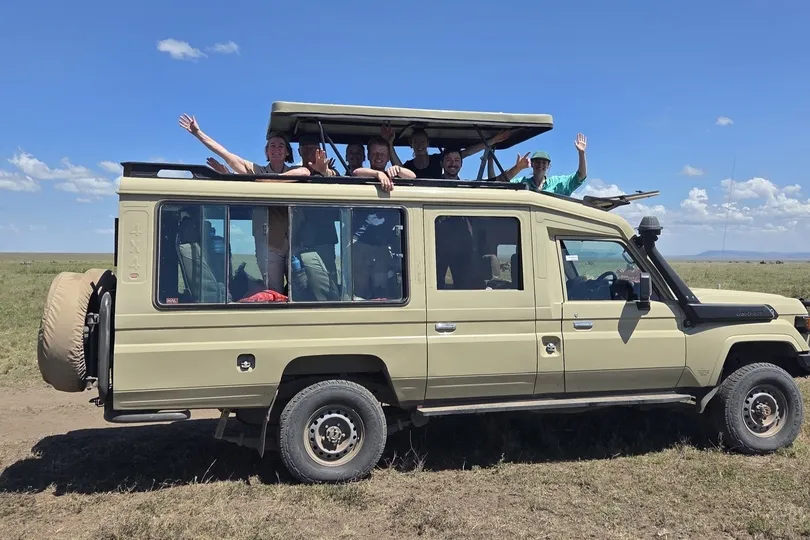 Familie zit blij in een safariwagen in Tanzania.