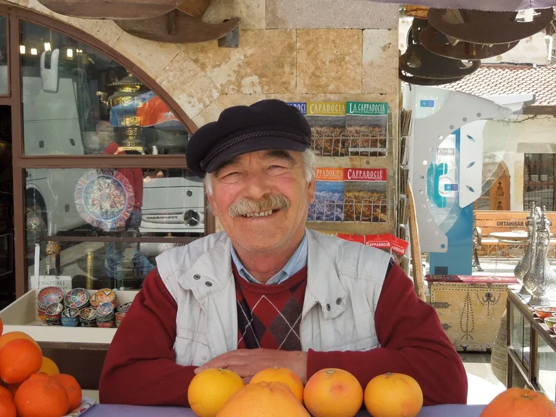 Een vriendelijke marktverkoper achter een kraam met vers fruit op een Turkse markt.