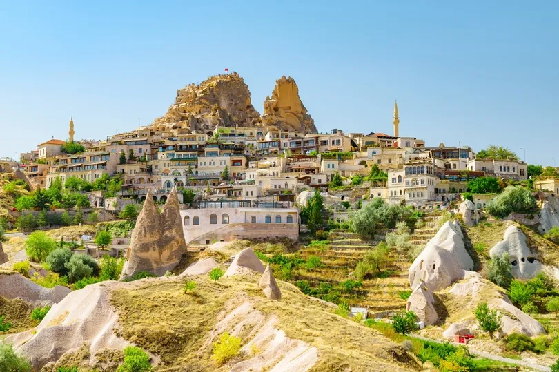 Uitzicht op rotsformaties, grotwoningen en een kasteel op een heuvel in Cappadocië.