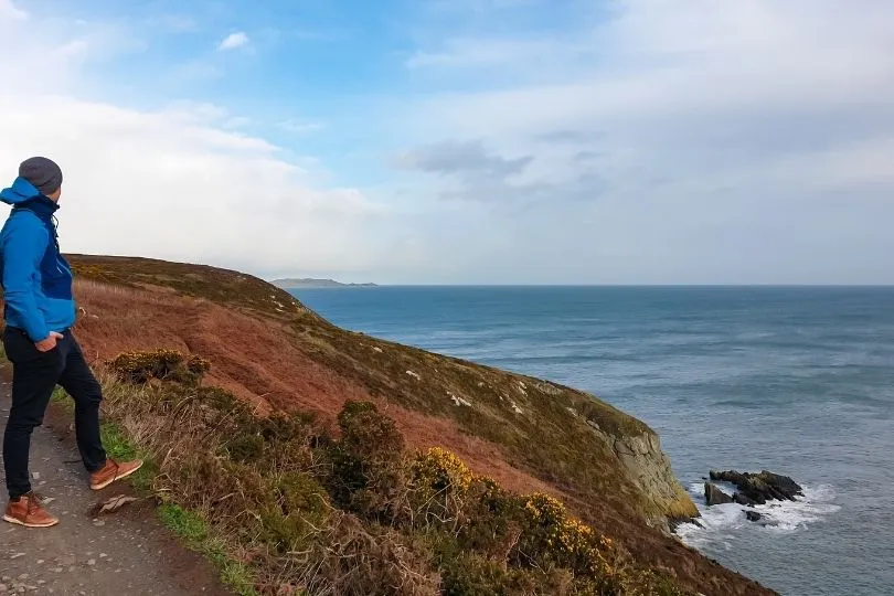 Man die langs de kust van Howth staat en uitkijkt naar het water.