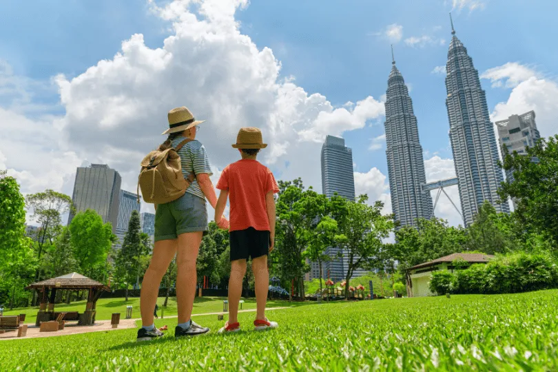 Vrouwelijke toerist die hand in hand staat met haar zoon kijkend naar de skyline van Kuala Lumpur.