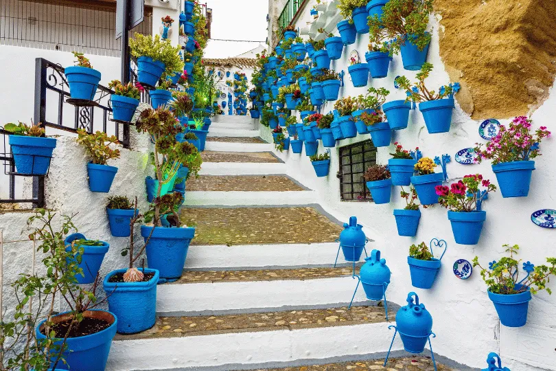 Wit smal straatje met blauwe bloem potten aan de muur in Córdoba.