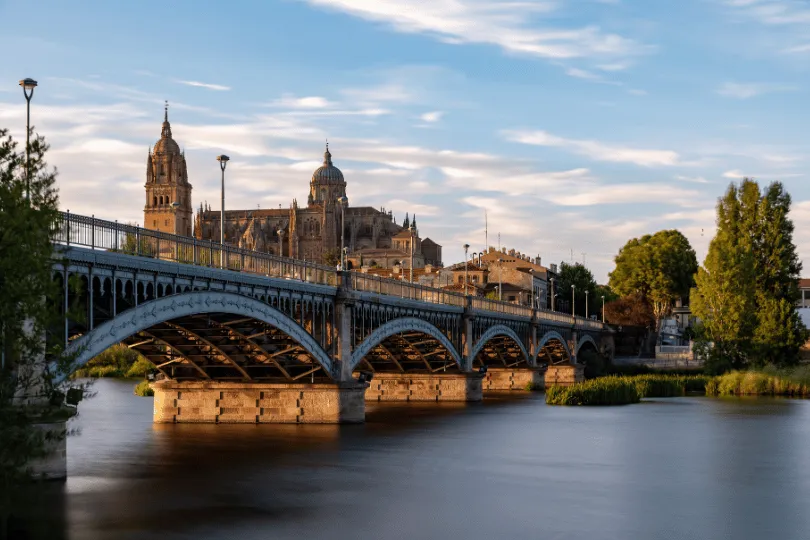 Uitzicht op Salamanca (Spanje) bij zonsondergang, met de kathedraal en de Enrique Estevan-brug vanaf het uitkijkpunt van de pier aan de rivier de Tormes.