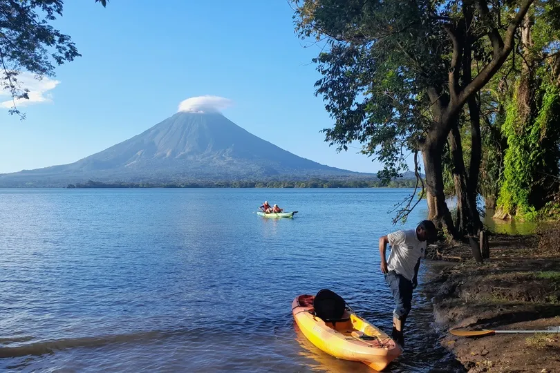 Reizigers kajakken op een meer met uitzicht op een vulkaan in Nicaragua.