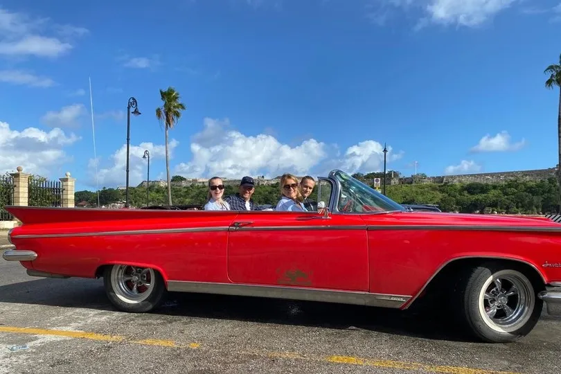 Familie in een rode auto in Cuba.