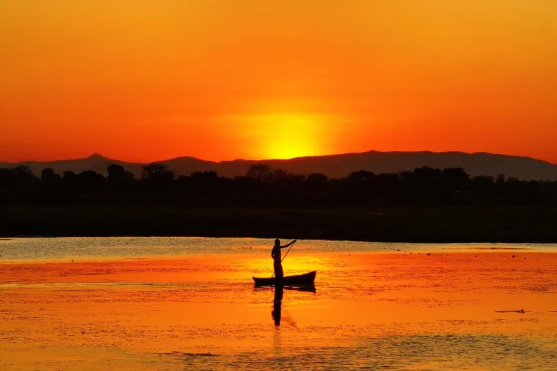 Man is aan het kajakken in Malawi met een mooie zonsondergang.
