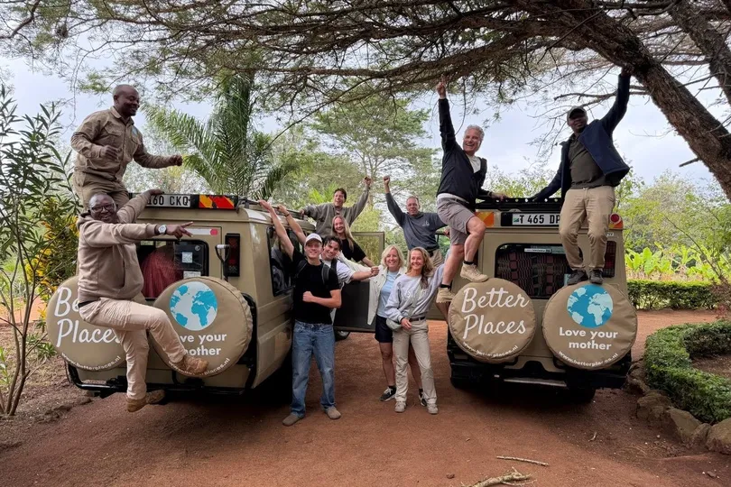Blije reizigers met hun gidsen en safariwagens in Tanzania.