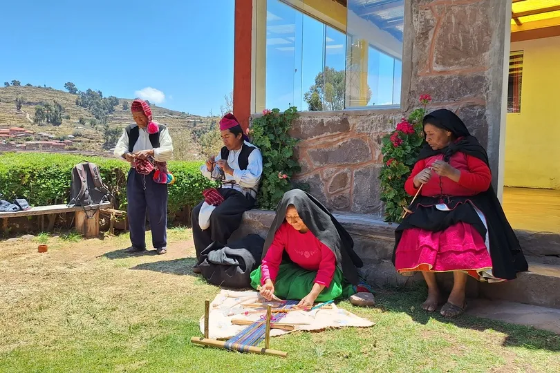 Bewoners weven traditionele kleding op Taquile bij het Titicacameer.