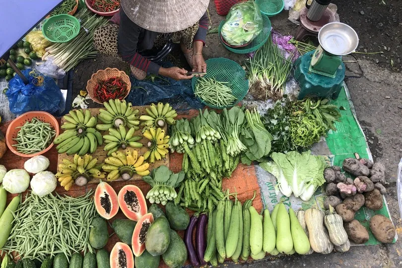 Vrouw is groente aan het snijden op de markt. 