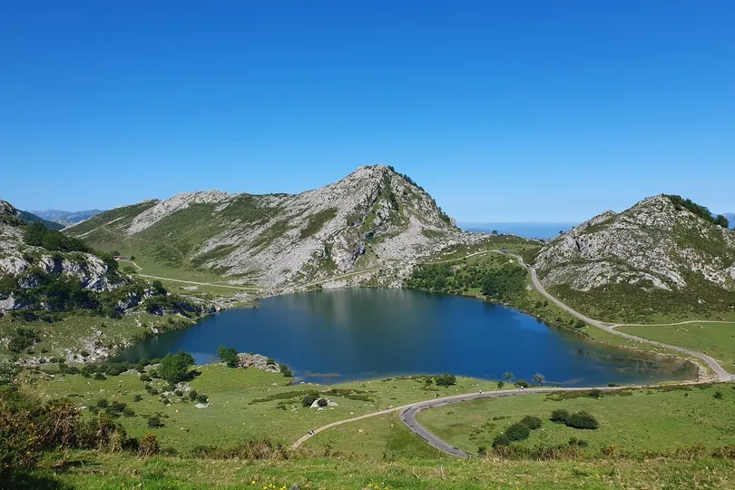 Meer omringt door bergen en grasvelden.