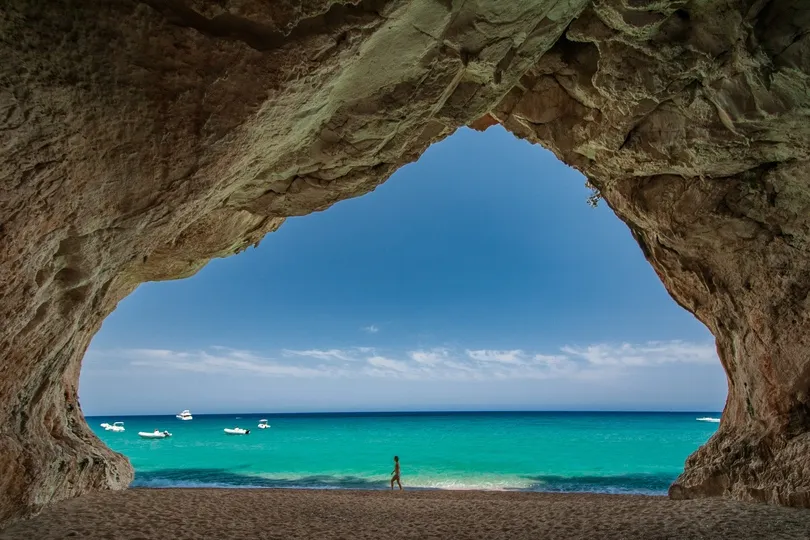 Uitzicht vanuit een grote rotsgrot op het turquoise zeewater en de boten voor de kust van Dorgali op Sardinië.