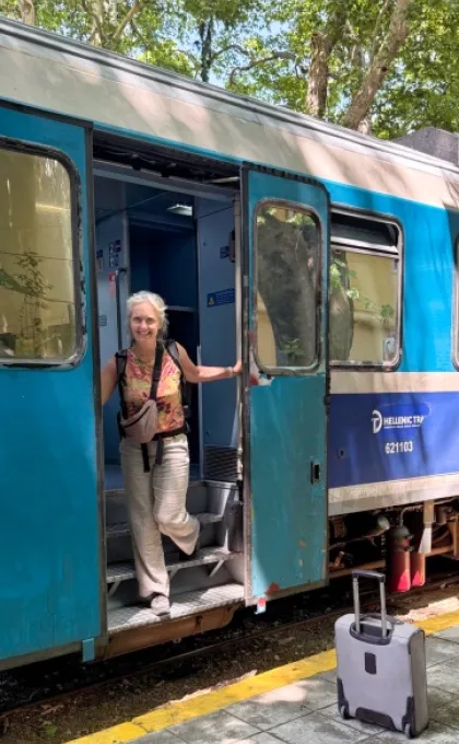 En vrouw met een koffer stapt in de trein naar Griekenland.