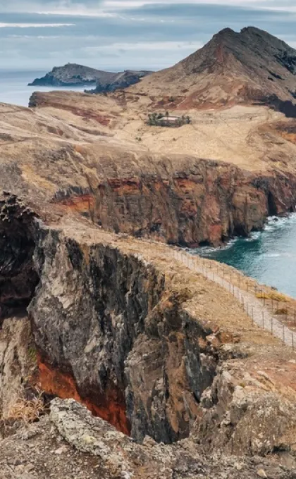 Een ruig kustpad slingert over de vulkanische kliffen van Ponta de São Lourenço, met uitzicht op de azuurblauwe oceaan van Madeira.