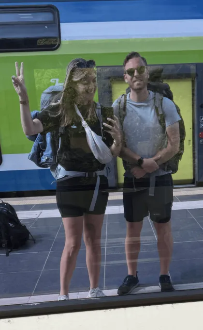 Twee mensen poseren in de reflectie van de trein.