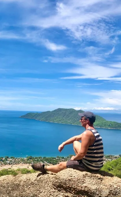 Reisexpert Dilo die uitkijkt op de zee zittende. 