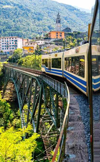 Italië, met de trein naar Toscane over een brug door landschap met bergen en dorpjes.