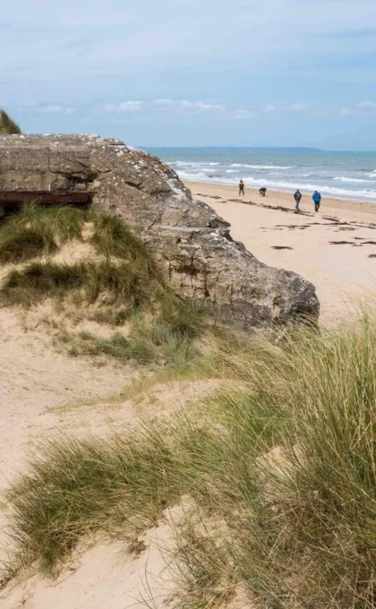 Wandelen langs de D-Day stranden - wandelaars en ruïnes op het Utah strand in Normandië.