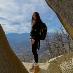 Vrouw staat op een rots in de natuur.
