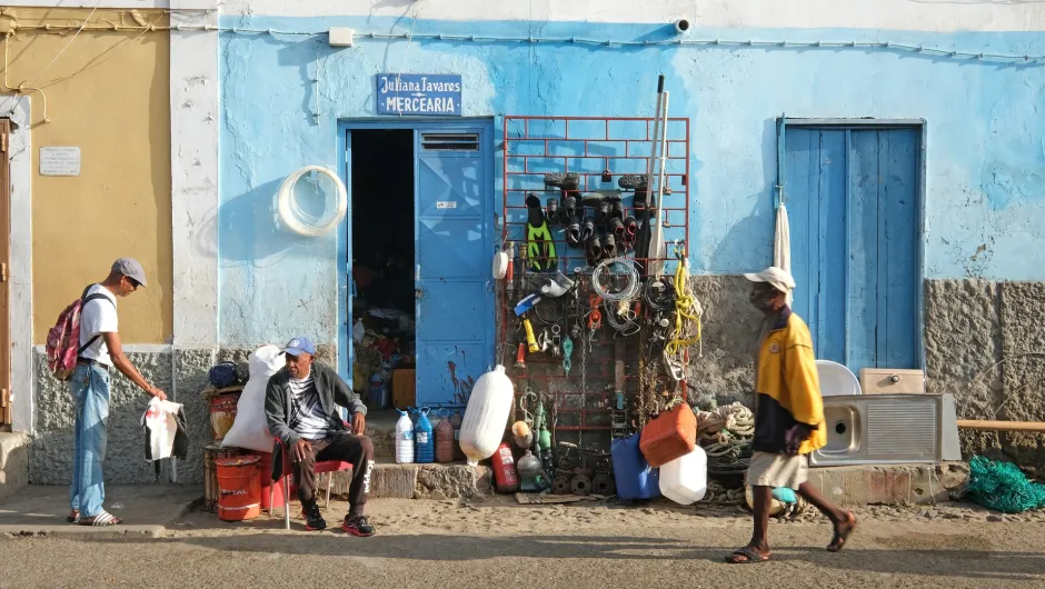 Drie mannen zitten voor een blauw huis in Kaapverdië.