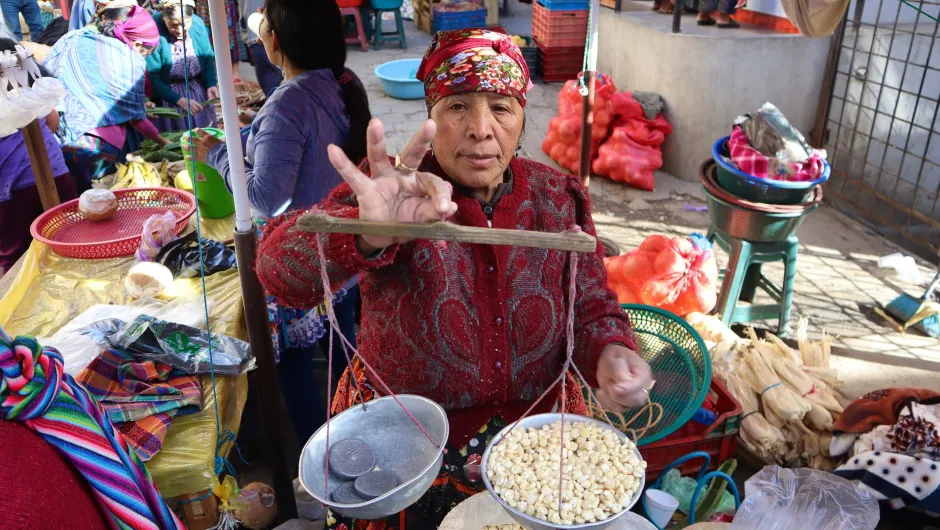 Vrouw met weegschaal op markt in Guatemala.