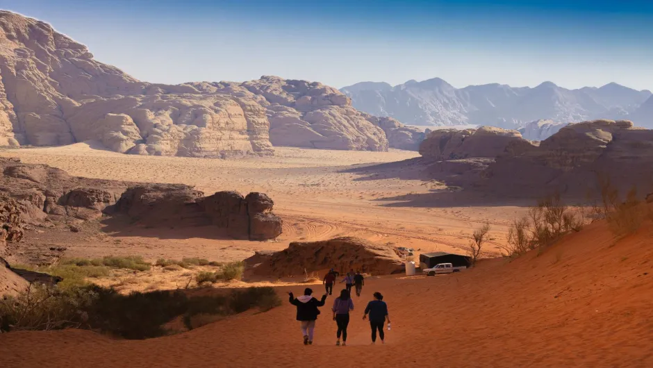Eine Gruppe Menschen läuft einen Hügel in der jordanischen Wüste hinab.