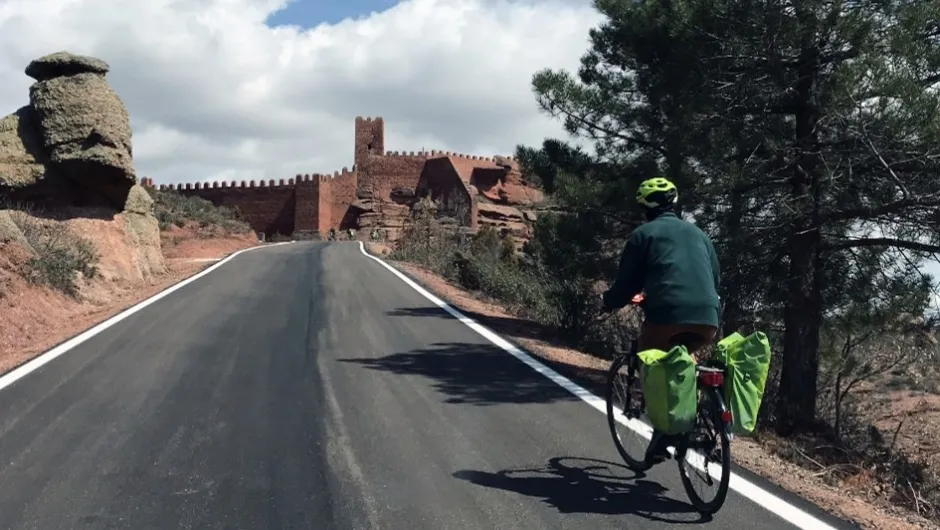 Fietsvakantie Aragón en Valencia - fietser in Peracense met kasteel op de achtergrond, Spanje.