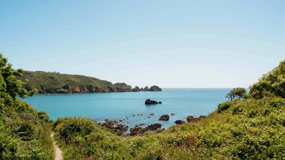 De beste reistijd kanaaleilanden, helder blauw water en rotsachtige eilanden in de verte.