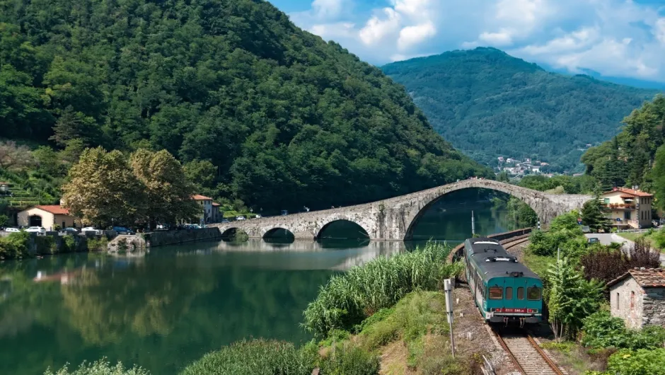 Italië, Toscane, trein door de bergen langs een rivier met brug.