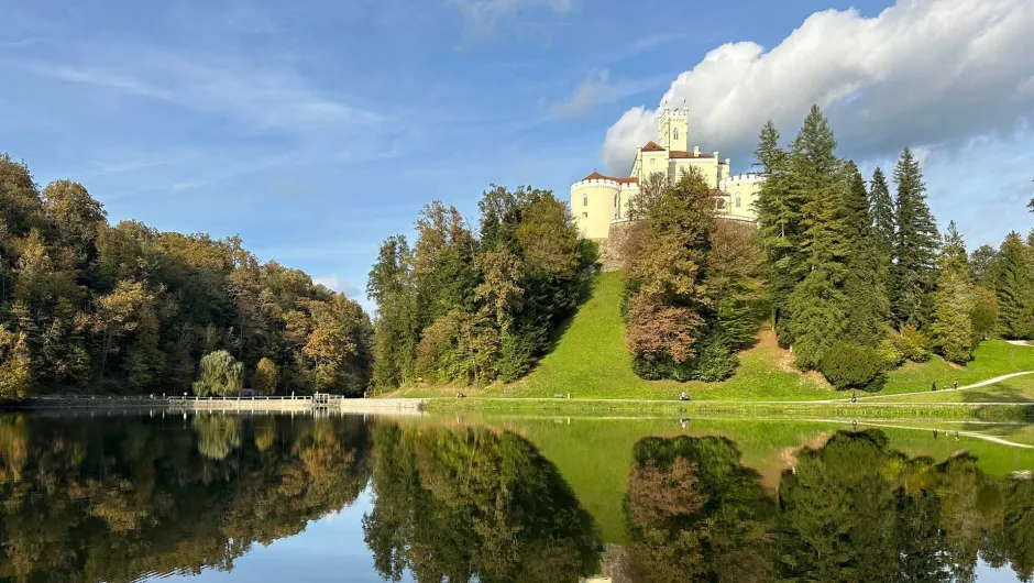 Een kasteel ligt op een heuvel en weerspiegelt in een rustig meer.