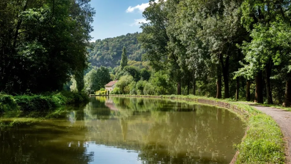 Kanaal van Bourgogne tussen de groene bomen en bergen van het landschap van Frankrijk met aan de rechterkant een fietspad. 