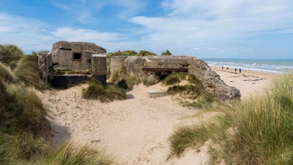 Wandelen langs de D-Day stranden - wandelaars en ruïnes op het Utah strand in Normandië.