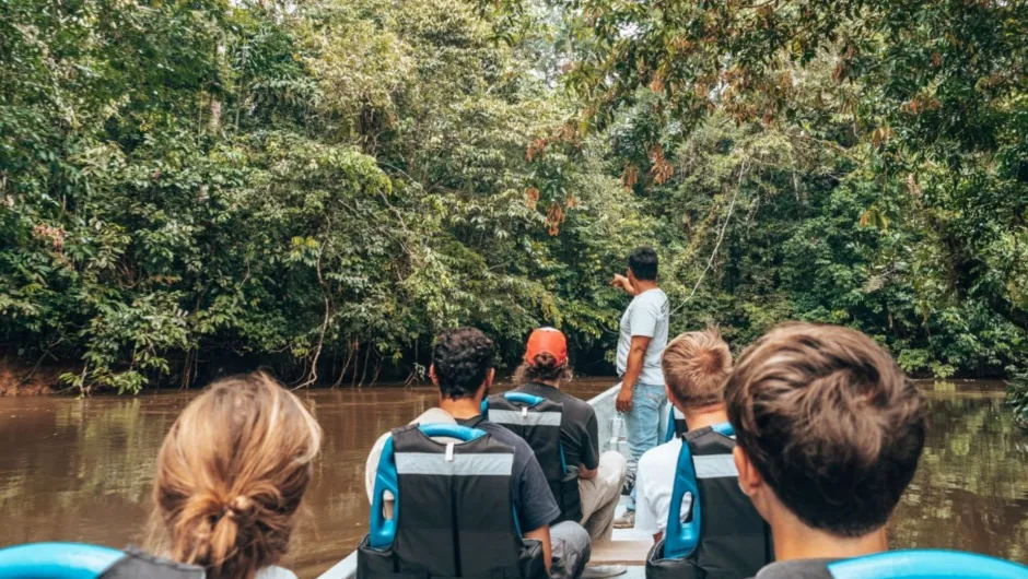 Familie in een bootje dat aan het varen is door de jungle. 
