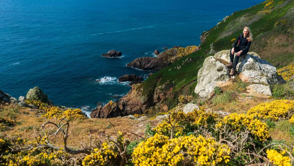 Vrouwelijke hiker op een steen bij de kust van Guernsey.
