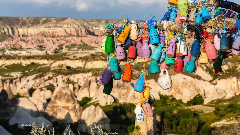 Een boom vol kleurrijke aardewerken potjes met uitzicht op het bijzondere rotslandschap van Cappadocië.