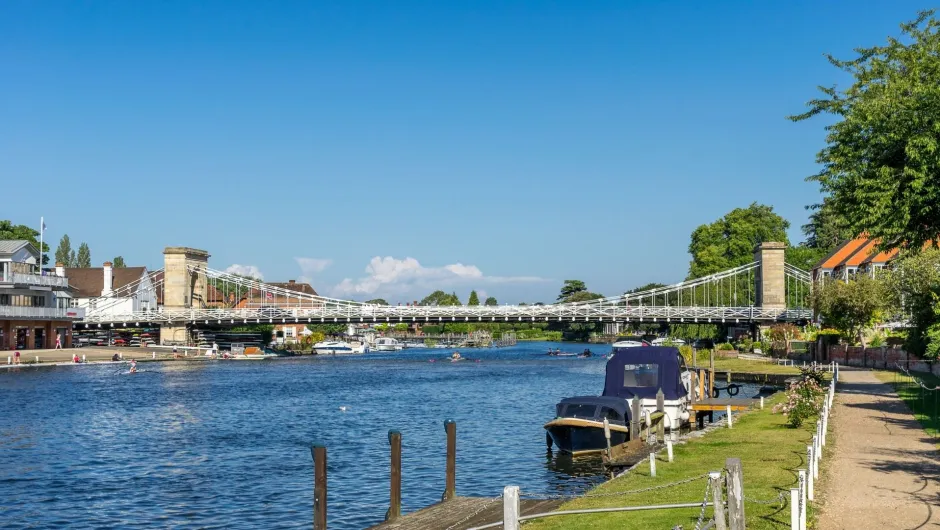 Een rivier met een hangbrug en bebouwing langs de oevers.