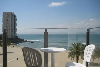 Foto vanaf een balkon van een hotel in Cullera met stoelen en een strand op de achtergrond.