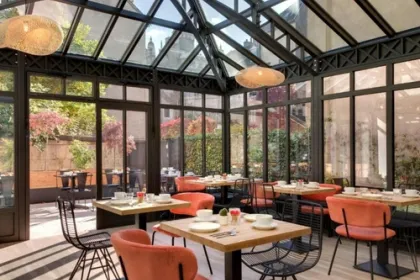 Restaurant van Hotel Des Ducs in Dijon, Bourgogne, met een glazen veranda met daarbuiten veel groene planten en een blauwe lucht.