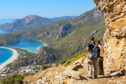 Twee reizigers wandelen de Lycian Way in Turkije en staan stil bij de kust om naar het uitzicht te kijken.