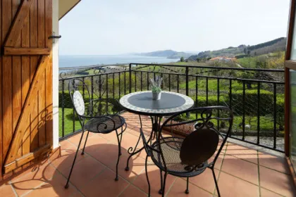 Balkon met tafel en stoelen en zee.