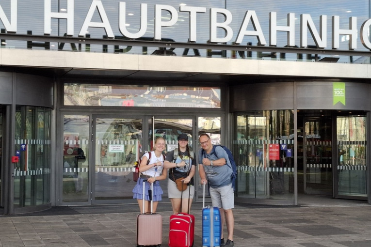 Drie reizigers staan voor het treinstation.