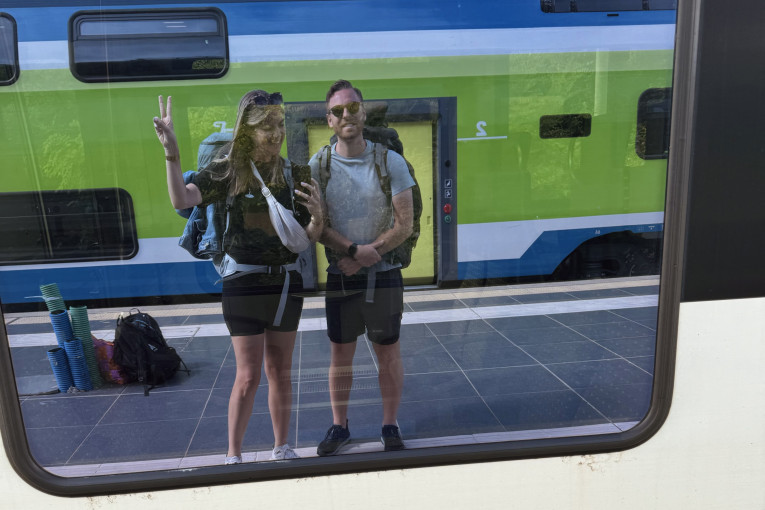 Twee reizigers poseren in de reflectie van het raam van de trein.