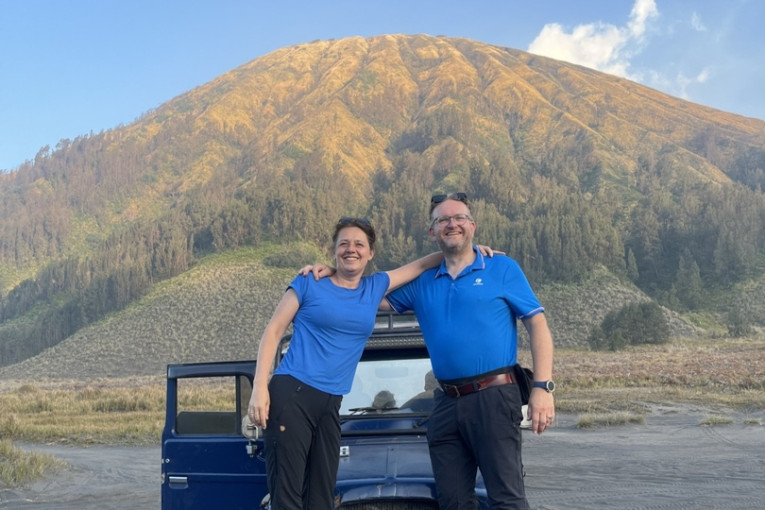Twee reizigers staan voor een auto in Indonesië.